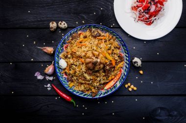 Karanlık bir arka plan üzerinde şark süsleme ile pilav ve salata achichuk plaka üzerinde. Orta-Asya Mutfağı - Plov. Üstten Görünüm