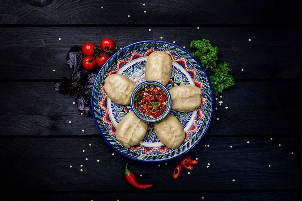 Albóndigas al vapor tradicionales Manti en plato con adorno oriental con salsa de tomate. Vista superior. Fondo de madera oscura — Foto de Stock