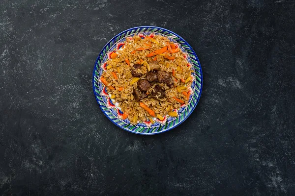 Пилаф на тарелке с восточным орнаментом на темном фоне. Центрально-Азиатская кухня - Плов. Вид сверху — стоковое фото