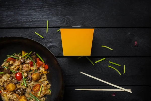 Stir fry nudlích s mořských plodů a zeleniny wok pánvi na černém pozadí dřevěná. Box na nudle — Stock fotografie