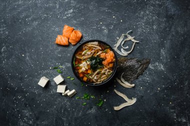 Japon miso çorbası ile tofu ve somon malzemelerle vintage renkli arka plan üzerinde siyah bir kase. Üstten Görünüm