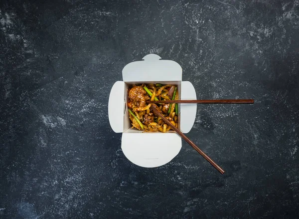 Udon stir fry noodles with chicken in a box on a vintage colored background. Top view. With chopsticks — Stock Photo, Image