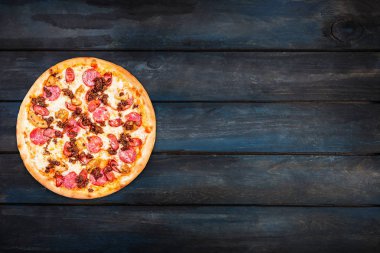 Güzel pizza et karışımı tütsülenmiş sosis, tavuk, kıyma ve koyu ahşap zemin üzerine biberli. Üstten Görünüm