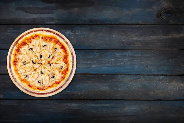 Вкусная пицца с грибами и курицей на деревянном подставке на темном фоне. Ориентация сверху с левой стороны — стоковое фото