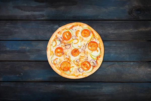 Perfekte Pizza mit Tomatenscheiben, Zwiebeln und Paprika auf dunklem Hintergrund. Orientierung im Zentrum von oben — Stockfoto
