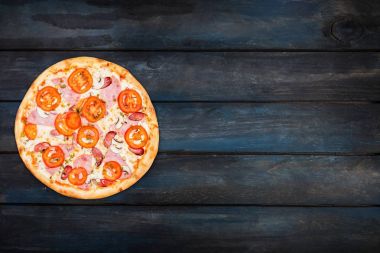 Mükemmel klasik pizza jambon, mantar ve karanlık bir arka plan üzerinde domates. En iyi görünüm yönlendirmesini sol tarafında