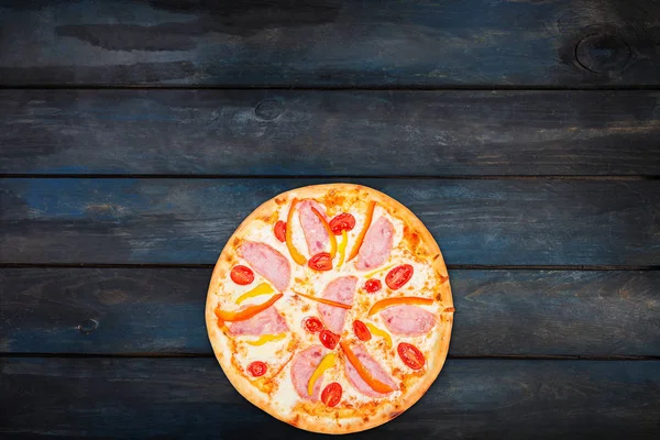 Deliziosa pizza con prosciutto peperoni dolci e pomodori su uno sfondo di legno scuro. Vista dall'alto orientamento verso il basso — Foto Stock