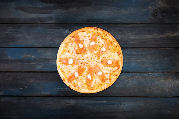 Leckere Pizza mit Lachs und Philadelphia-Käse auf dunklem Holzgrund. Orientierung im Zentrum von oben — Stockfoto