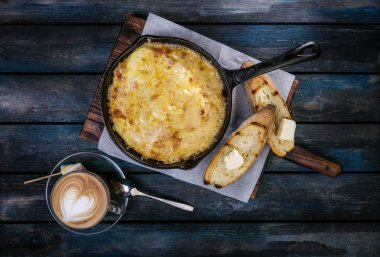 Kahvaltı. Bir tavada tost ve kahve ile ahşap bir stand üzerinde klasik omlet. Renkli ahşap arka plan. Üstten Görünüm