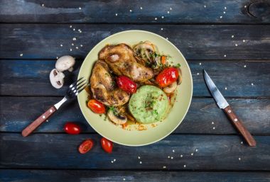 Kavrulmuş tavuk sebze ve yeşil patates püresi. Çatal, bıçak renkli ahşap arka plan üzerinde. Üstten Görünüm