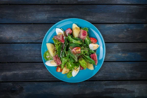 Insalata con verdure e bistecca di tonno su un bel piatto blu. Fondo in legno colorato. Vista dall'alto — Foto Stock