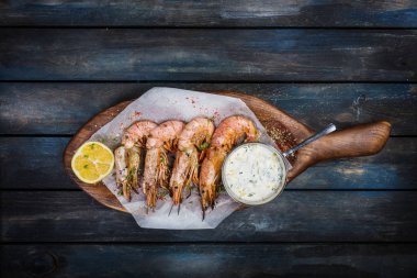 Büyük kırmızı Arjantinli karides veya bilinenlerin bir ahşap tahta üzerinde yarım limon ve beyaz sos ile. Üstten Görünüm