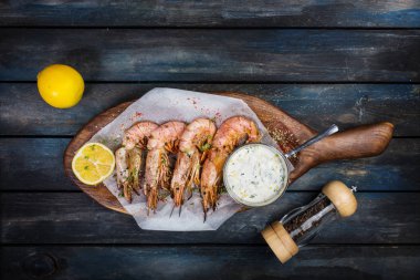 Lezzetli Arjantinli karides veya bilinenlerin beyaz sos biber-pot ve ahşap bir tahtada yarım limon ile. Üstten Görünüm