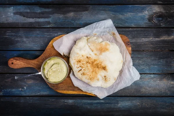 Hidangan pembuka tradisional Timur Tengah Hummus disajikan dengan roti pita segar. Di papan kayu. Tampilan atas — Stok Foto