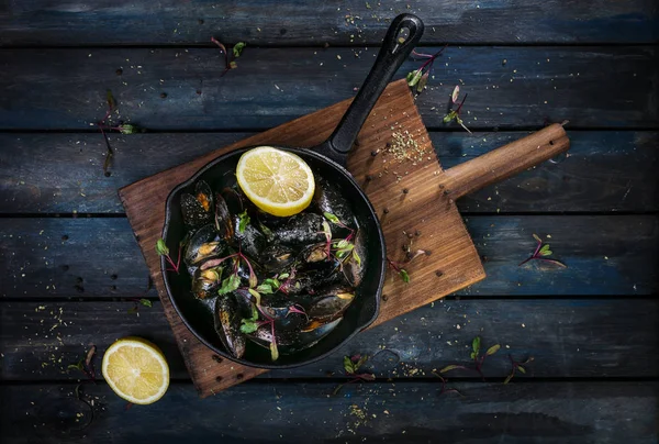 Lezzetli midye. Sıcak bir tava otlar baharat ve limon renkli ahşap zemin ile hizmet veren. Üstten Görünüm