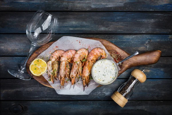 Büyük karides veya bilinenlerin beyaz sos biber pot cam şarap ve bir ahşap tahta üzerinde yarım limon ile. Üstten Görünüm