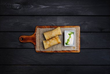 İnce doldurulmuş krep veya ekşi krema ile Rus blini. Ahşap bir gemide. Üstten Görünüm. Siyah ahşap arka plan