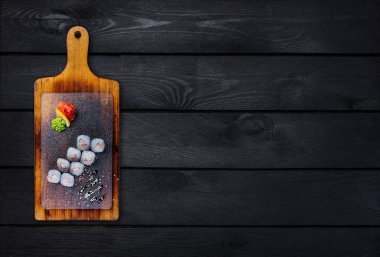 Klasik suşi rulo karides ile ahşap bir gemide. Üstten Görünüm. Siyah ahşap arka plan