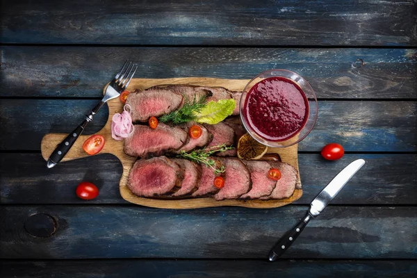 Gegrilltes Roastbeef mit Preiselbeersoße auf Schneidebrett mit Salz und Pfeffer. Ansicht von oben. — Stockfoto