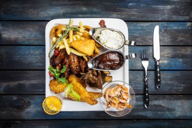 Açılan aperatifler kompozisyon suluguni patates kızartması ve Remoulade ve Barbekü tavuk kanatları, kuzu kaburga, sosis, yağda kızartılmış karides, soğan halkaları, nuggets balık ve hindi, kalamar halkaları,