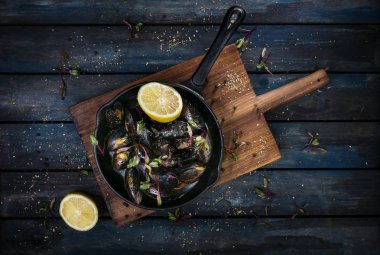 Lezzetli midye. Sıcak bir tava otlar baharat ve limon renkli ahşap zemin ile hizmet veren. Üstten Görünüm