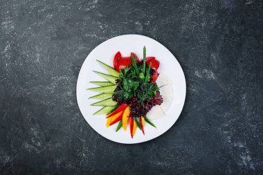 Keçi peyniri dilimlenmiş sebze ile beyaz tabakta.