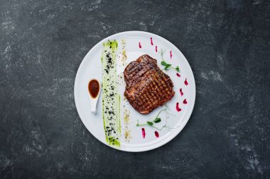 Beyaz bir tabak ızgara sığır eti biftek.
