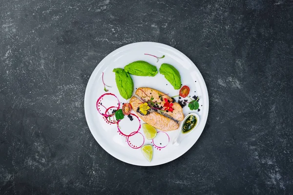 Beyaz tabakta bezelye püresi ile ızgara somon.