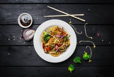 Udon stir fry erişte et ya da tavuk ve sebze yemek çubukları ile beyaz bir plaka ile.