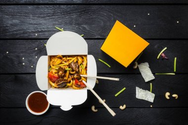 Udon heyecan fry erişte ile et ya da tavuk bir kutu içinde. Siyah arka plan. Yemek çubukları ve sos ile.