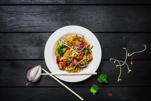 Udon stir fry erişte et ya da tavuk ve sebze yemek çubukları ile beyaz bir plaka ile.