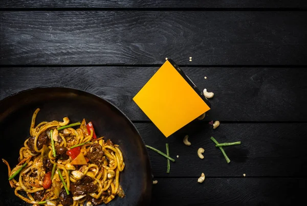 Udon mexa macarrão frito com carne ou frango e legumes na panela wok. Com uma caixa para macarrão — Fotografia de Stock