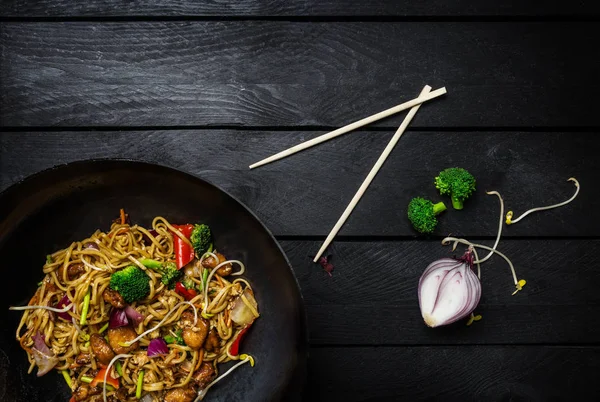 Stir fry noodles in traditional Chinese wok, chopsticks and ingredients. Space for text. — Stock Photo, Image