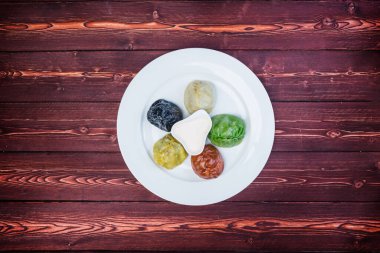 Ahşap arka planda renkli oryantal hamur tatlısı ve sos tabağı. Üst görünüm