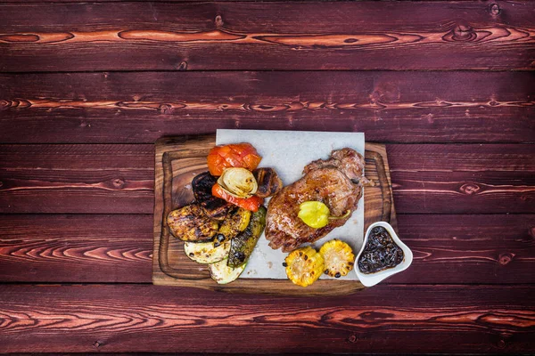 Delicioso bife grelhado com legumes assados variados e milho com molho. Vista superior Imagem De Stock