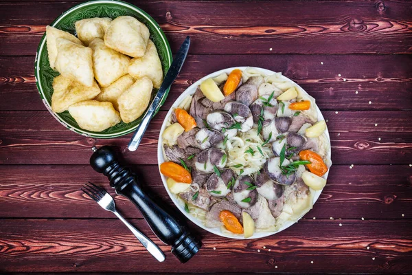 Baursak ile beslenme yemeği - geleneksel Kazak Asya yemeği ve ulusal ekmek. Masadaki tabakta kuzu etli ve soğanlı erişte. Yatay üst görünüm