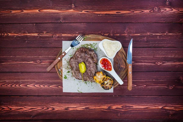 Delicioso filete a la parrilla con salsas y maíz frito. Hay una cubertería. Vista superior — Foto de Stock