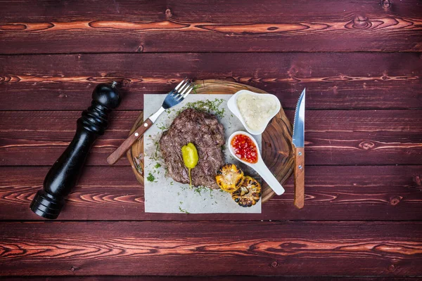 Delicioso bife grelhado com molhos e milho frito. Há um moedor de pimenta e talheres. Vista superior Fotografia De Stock