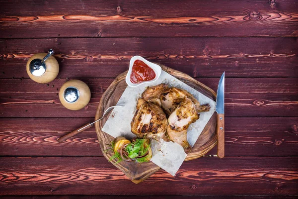 Asado frito a la parrilla Tabaco de pollo sobre tabla de cortar sobre fondo de madera. Hay una picadora de pimienta y cubiertos. Vista superior — Foto de Stock