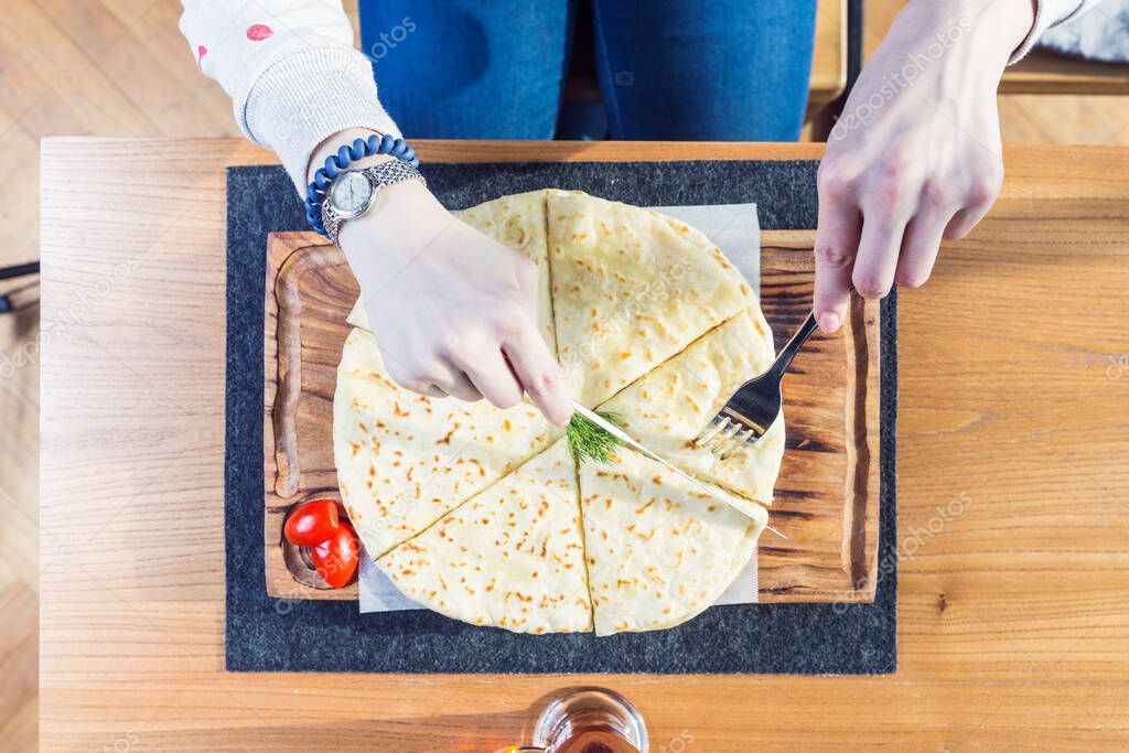 hychiny, tortilla dough with cheese and potatoes, on cutting board. Female hands Top view on a wooden background