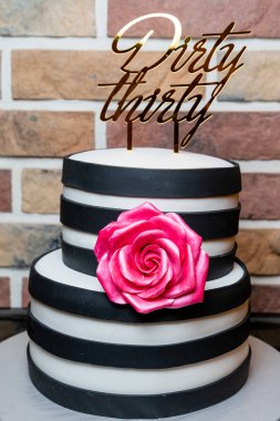 İki katlı, önünde bir gül olan siyah beyaz bir pasta..
