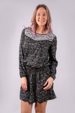 Siyah ve gri elbiseli bir kız, beyaz bir arka planda izole edilmiş..