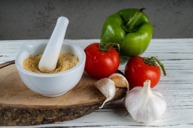 Gri bir arka planda beyaz bir stupada kurutulmuş sarımsak tozu..