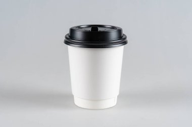 Tek kullanımlık, beyaz bardakta siyah kapaklı, beyaz arka planda izole edilmiş..