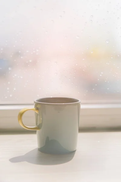 Coffee cup on table with rain drop  on window background,retro e