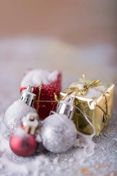 Glänsande gyllene julgranskulor och röda, guld presentaskar över snö b — Stockfoto