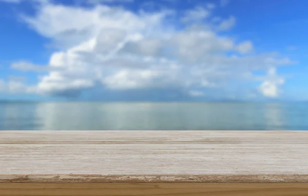 木製テーブルの上夏青いビーチ上空の背景がぼやけてください。 — ストック写真