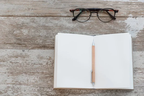 Leeres Notizbuch, Bleistift und Brille auf Grunge-Holzgrund — Stockfoto