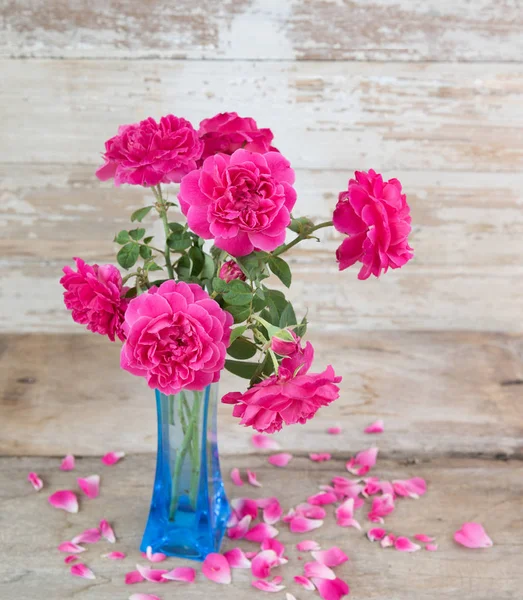 グランジ木製の上に青い花瓶にピンクのバラの花のある静物 — ストック写真