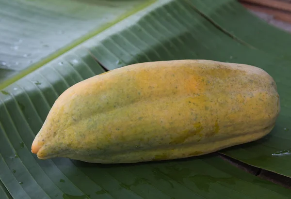 Świeżym papai owoców na zielonych bananów pozostawić podłoże, Martwa natura — Zdjęcie stockowe